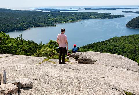 Visitors overlook islands from a mountain summit.