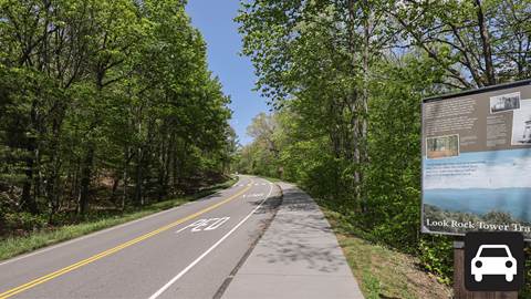 A road through the woods with a sign for Lookrock tower on the right