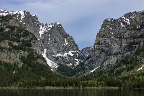 A rocky, mountain canyon sits across a calm lake.
