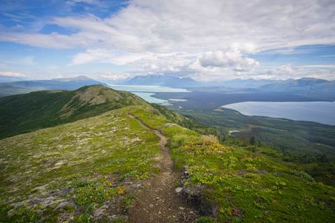 A footpath through green tundra with expansive views of two lakes behind